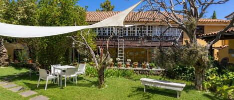 A courtyard with a white table and chairs, a bench, and a variety of potted plants.