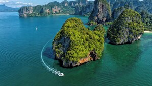 An aerial view of a coastal area with large, green, forested islands surrounded by clear blue water.