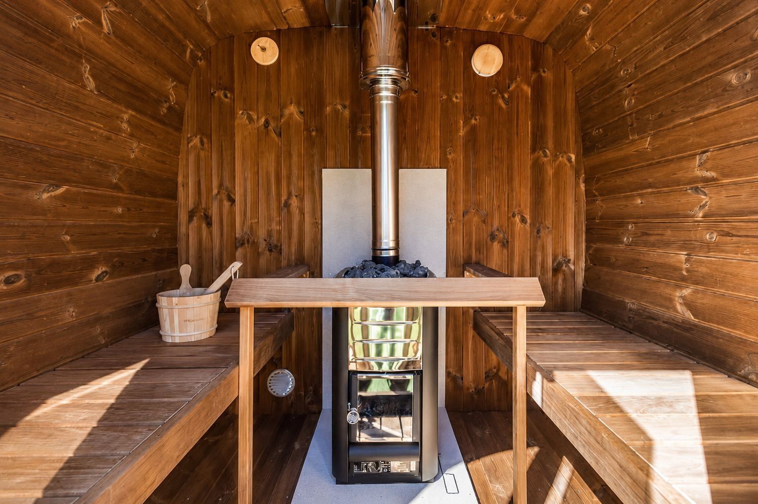 A sauna with a wooden interior, a table, and a sauna heater.