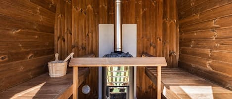 Eine Sauna mit Holzvertäfelung, einem Tisch und einem Saunaofen.