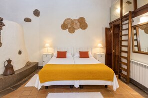 Ein Hotelzimmer mit einem Bett, zwei Nachttischen, einer Lampe, einer Wanddekoration, einem Spiegel und einer Leiter.