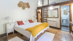 A bedroom with a bed, two bedside tables, a mirror, a ladder, and a bathroom visible through an open door. - GuestReady - Las Calas 3 Double Room Peonia (Las Palmas de Gran Canaria)