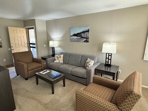 Ein Wohnzimmer mit einer Couch, zwei Sesseln, einem Couchtisch und zwei Lampen.