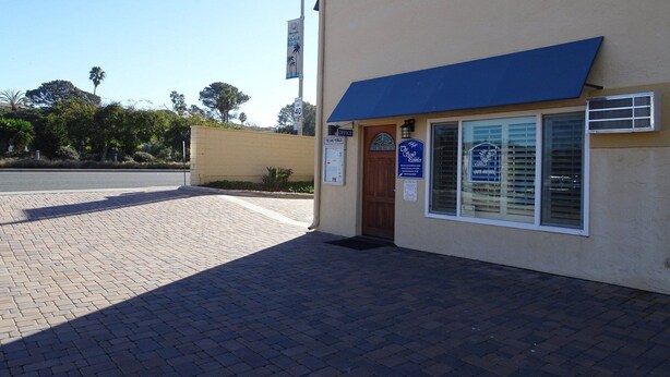 A building with a blue awning, a sign for 'The Grateful Guys,' and a speed limit sign of 40. - Machronicles Properties at Sand Pebbles Resort in beautiful Solana Beach (Solana Beach)