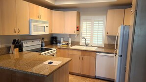 A kitchen with a central island, built-in oven, microwave, sink, and dishwasher. - Machronicles Properties at Sand Pebbles Resort in beautiful Solana Beach (Solana Beach)