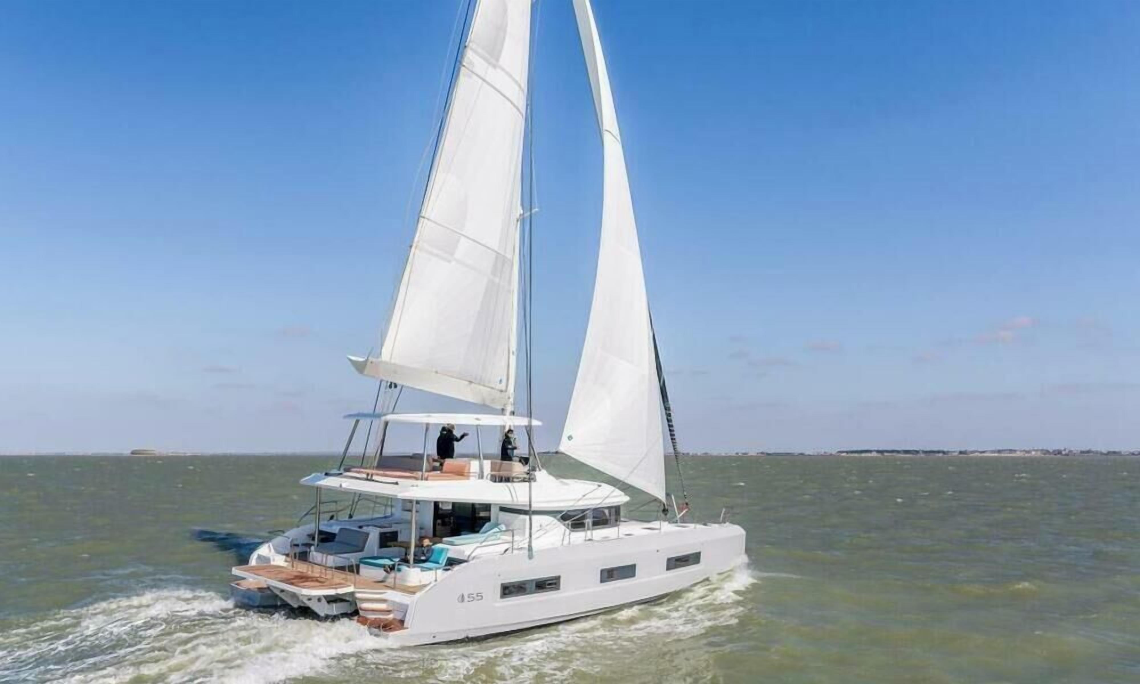 Un voilier blanc doté d’une cabine et de sièges sur le pont, naviguant sur des eaux calmes.