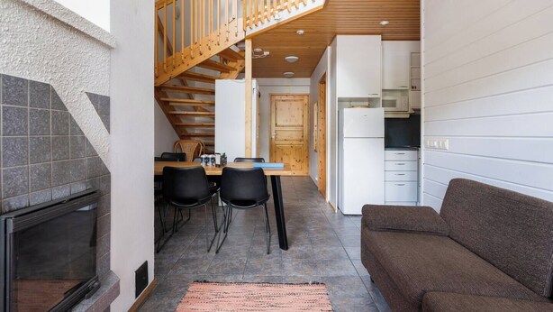 A compact living space with a kitchen, dining area, and a staircase leading to an upper level. - Alpine Kajo B5 by Aavalevi (Levi)