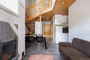 Un espacio habitable compacto con cocina, comedor y una escalera que conduce a un nivel superior.