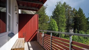 A balcony with a wooden bench, a red exterior wall, and a metal railing. - Alpine Kajo B5 by Aavalevi (Levi)