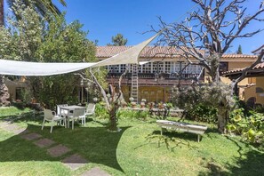 Een tuin met terras, een witte tafel en stoelen.
