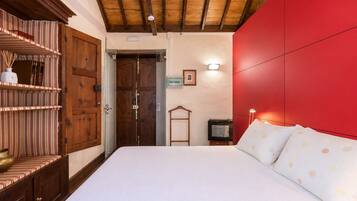 Une chambre avec un grand lit, une armoire en bois et un mur d’accent de couleur rouge.