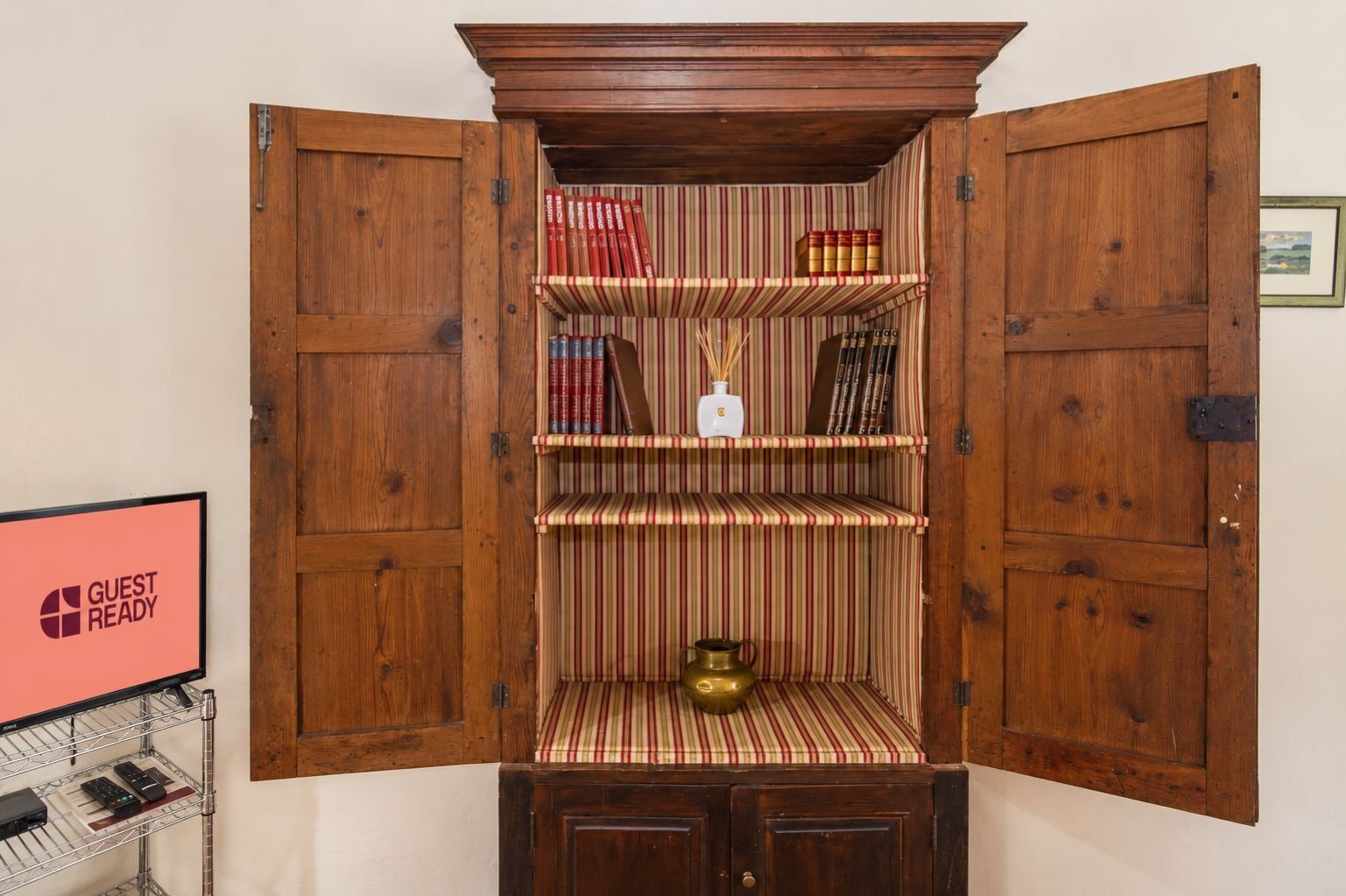 Un meuble en bois aux portes ouvertes, contenant des livres et un objet décoratif.
