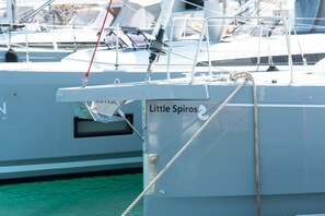 De boot 'Little Spiros' ligt afgemeerd in een jachthaven, met andere boten op de achtergrond.