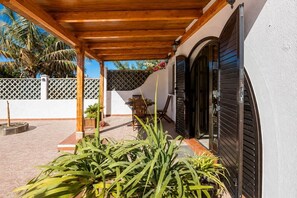 A covered outdoor area with a wooden ceiling, a seating arrangement, and a potted plant. - GuestReady - Duplex Turman Agaete Terrace (Agaete)