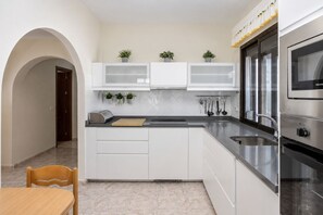 A modern kitchen with white cabinets, a marble countertop, and stainless steel appliances. - GuestReady - Duplex Turman Agaete Terrace (Agaete)