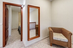 A hallway with a door, a mirror, and a wicker chair. - GuestReady - Duplex Turman Agaete Terrace (Agaete)