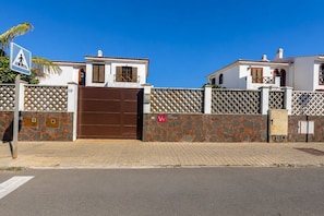 A residential area with a gated entrance, a pedestrian crossing sign, and a clear sky.
