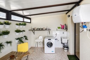 A compact laundry room with a washing machine, a sink, and a small table. - GuestReady - Duplex Turman Agaete Terrace (Agaete)