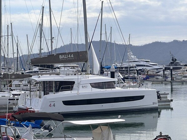 Un port de plaisance abritant de nombreux bateaux, dont un yacht blanc imposant baptisé « BALI 44 », doté d’une terrasse couverte.