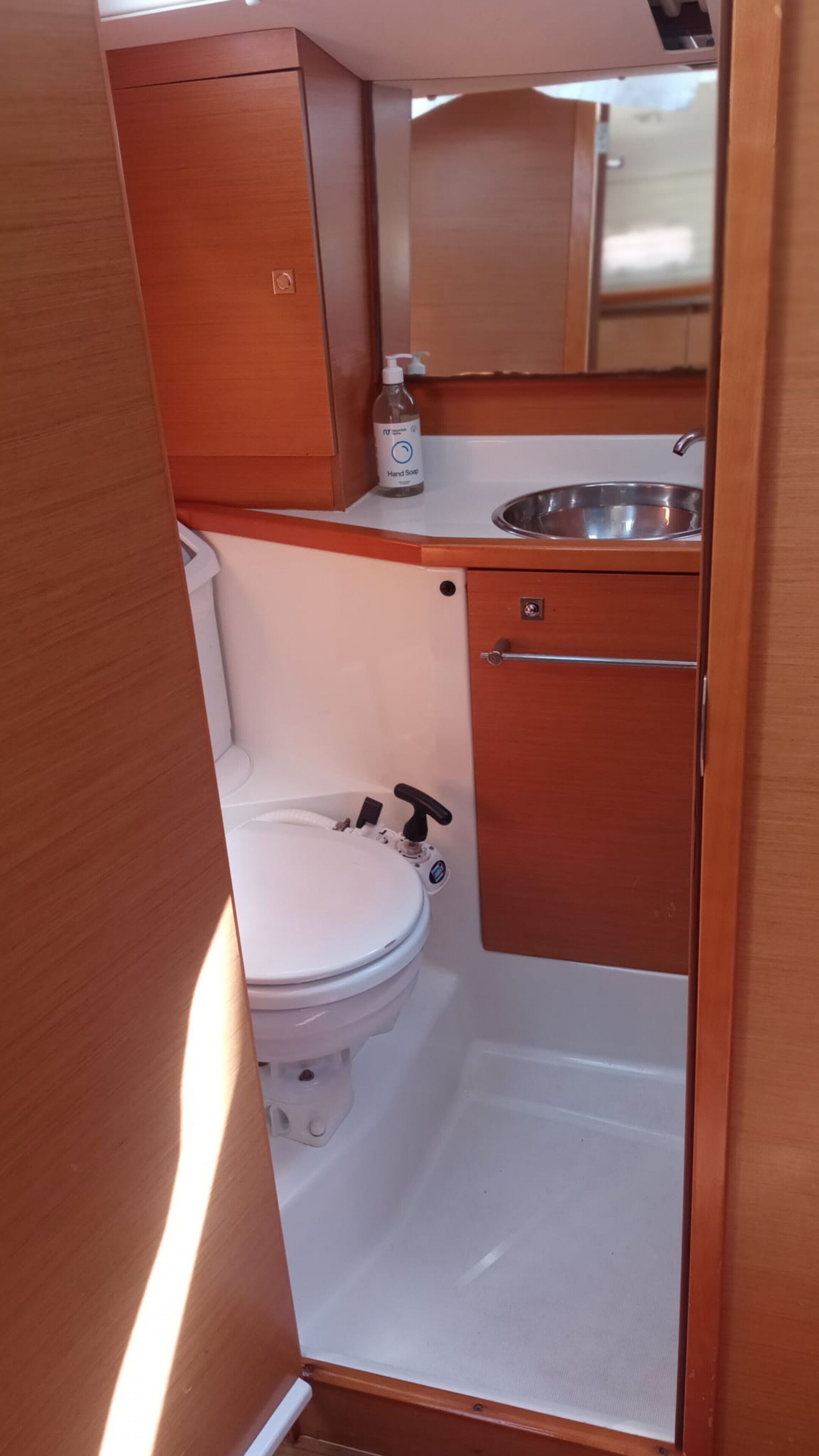 Une petite salle de bain comprenant des toilettes, un lavabo et un distributeur de savon liquide.