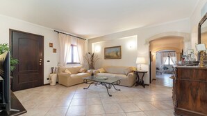 A living room with a sofa, coffee table, and a wooden cabinet. - Villa Sole D'Oro - pool, garden, and ocean view (Carrubazza-Motta)