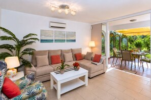 A living room with a sofa, coffee table, and a dining area with chairs and a table. - GuestReady - Sun Club Terrace and Pool (San Bartolomé de Tirajana)
