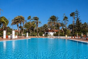 A clear blue pool surrounded by palm trees and lounge chairs. - GuestReady - Sun Club Terrace and Pool (San Bartolomé de Tirajana)