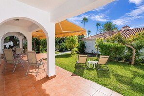Ein überdachter Patio-Bereich mit Gartenblick und Sitzgelegenheiten.