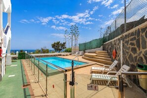 A swimming pool with a clear view of the sea, surrounded by lounge chairs and a stone wall. - GuestReady - Bello Horizonte Sea View and Pool (San Bartolomé de Tirajana)