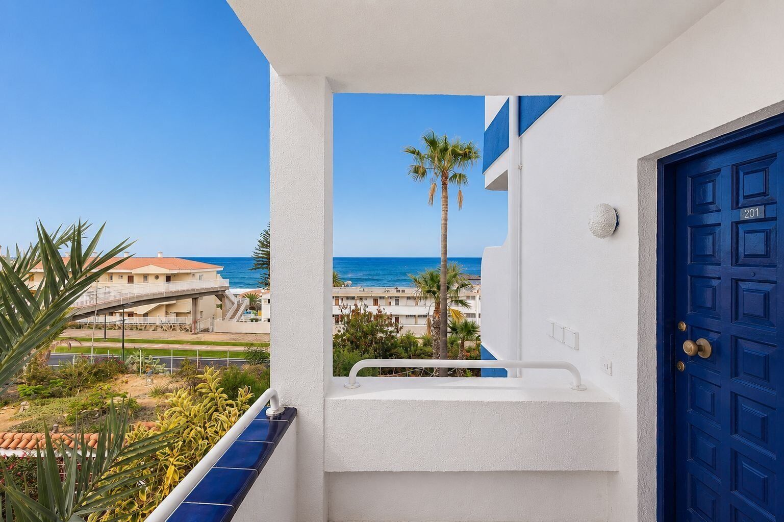 A balcony with a view of the sea and a blue door.