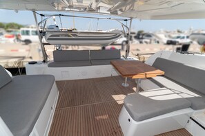 Interior de un barco con asientos, una mesa y zona cubierta para motor.