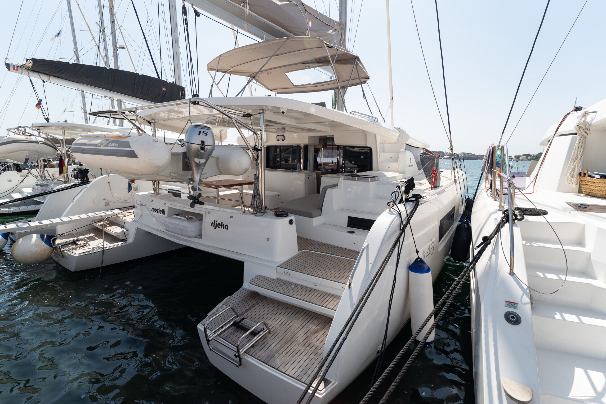 A yacht with a covered deck, seating area, and a small step leading to the water.