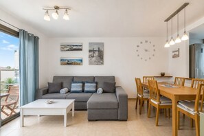 A modern living room with a grey sofa, a dining table with chairs, and a white coffee table. - GuestReady - Villa with Pool and Terrace (Costa Teguise)