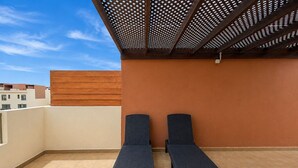 Eine Dachterrasse mit zwei Liegestühlen und einer Pergola.