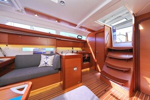 A compact, well-lit interior with a sofa, a small kitchenette, and a window providing natural light. - Sun-kissed Sailing Adventure in Split-Dalmatia, Croatia (Trogir)