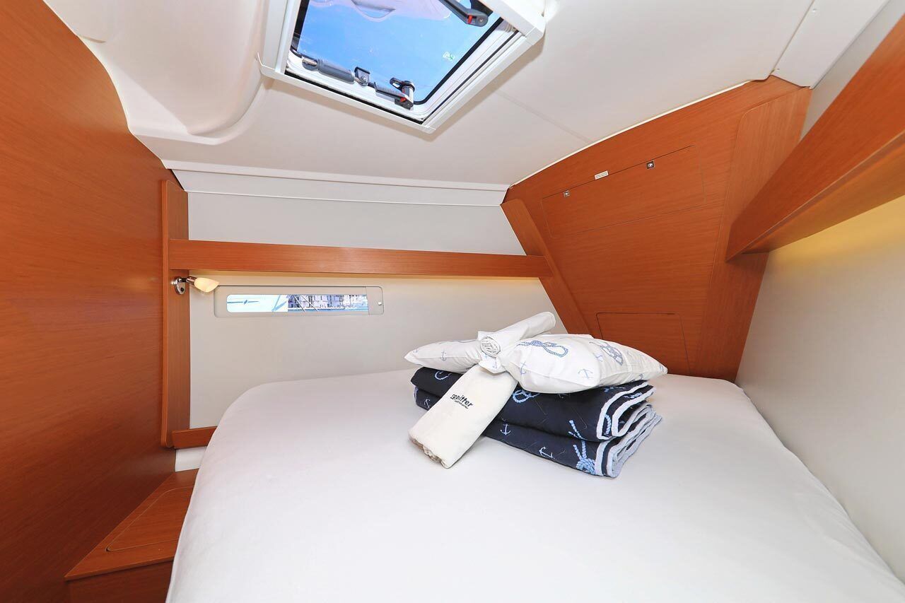 A compact cabin with a skylight, a bed with neatly folded towels, and a control panel.