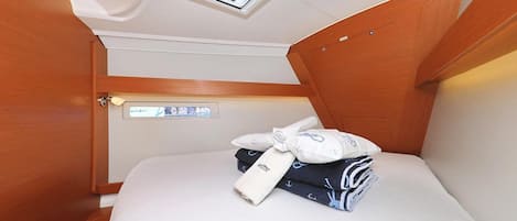 A compact cabin with a skylight, a bed with neatly folded towels, and a control panel.