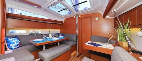 A yacht interior with a dining area, seating, and skylights.