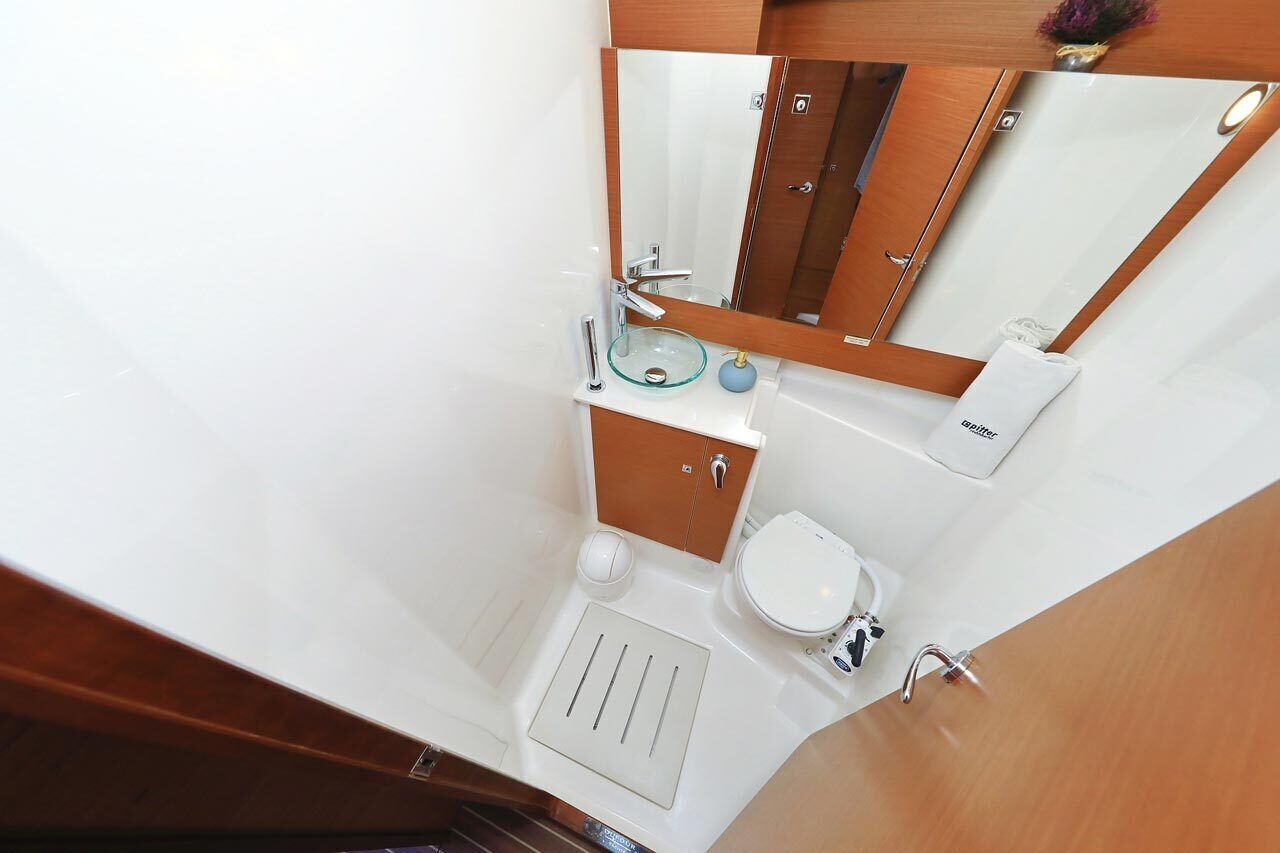 Un bagno con un lavandino in vetro, un water, uno specchio e un portaserviti.