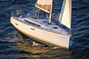 A sailboat on the water with two people on deck. - Sun-Kissed Sailing Adventure in Tenerife, Islas Canarias (Santa Cruz de Tenerife)