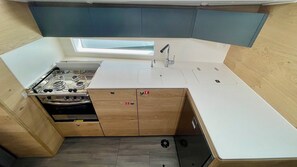 A compact kitchen with a gas stove, sink, and a small window above the countertop. - Sibenik Sun-soaked Sailing: A Luxurious Croatian Voyage (Pirovac)