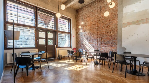An interior with wooden flooring, brick walls, and multiple tables and chairs.