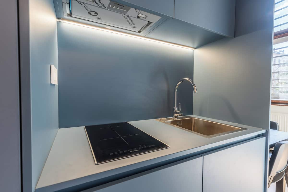 Una cocina moderna con una placa de inducción integrada, un lavamanos de acero inoxidable y una ventana sobre el lavamanos.
