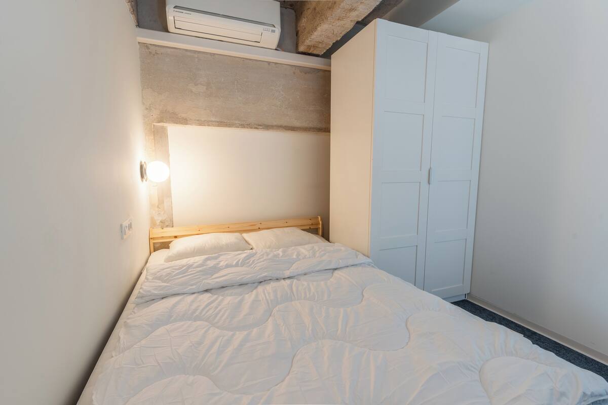 Un dormitorio con cama, armario y aire acondicionado de pared.