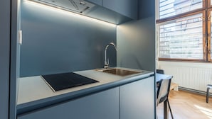 A modern kitchen with a built-in stove, a sink, and a window with blinds.