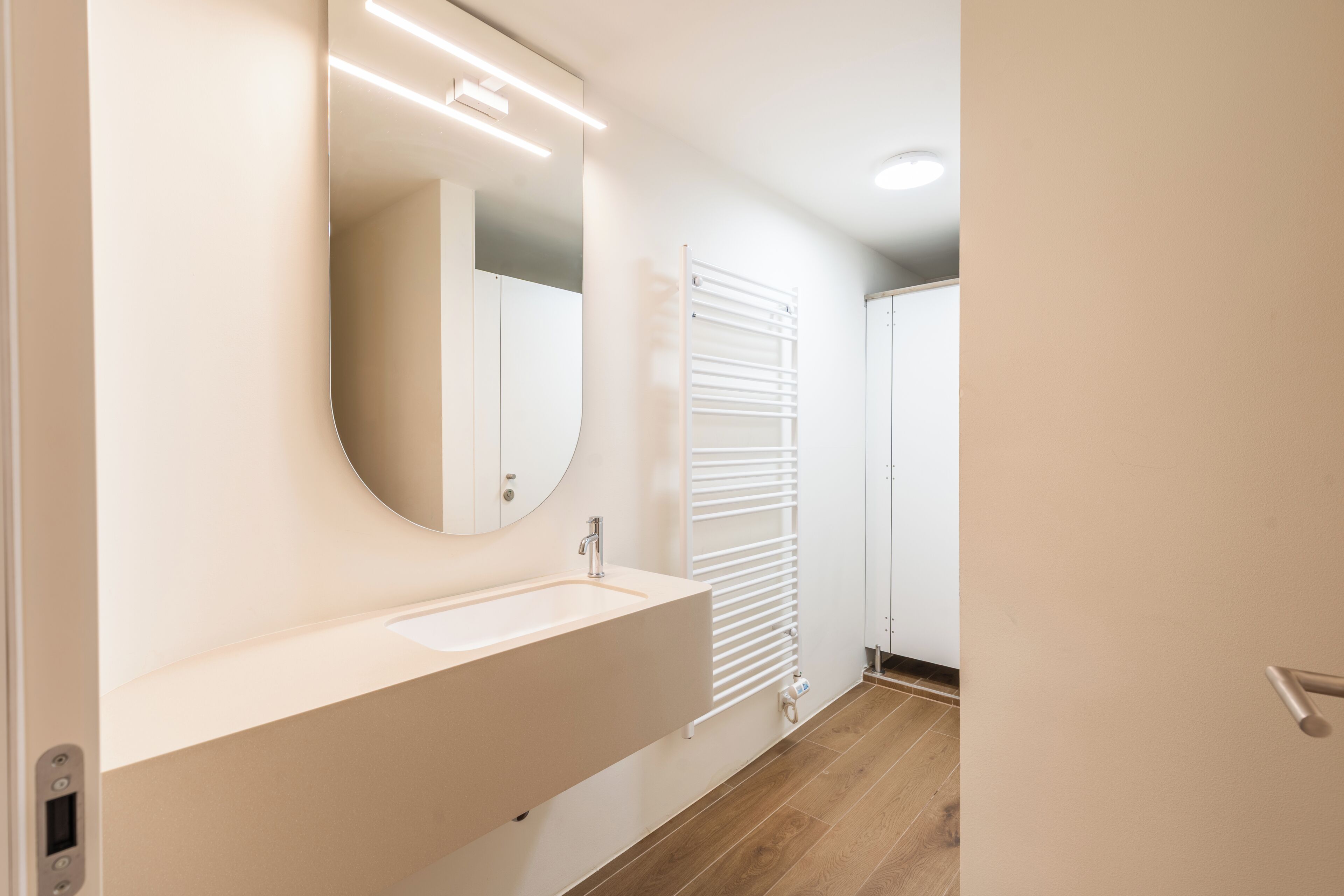 A bathroom with a white sink, mirror, and towel rack.