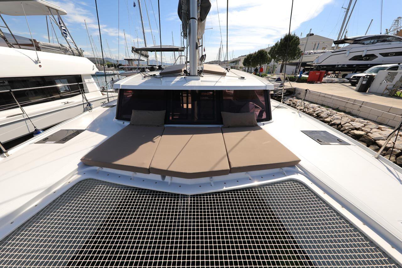 Un pont de bateau avec un espace de repos couvert, un mât et d’autres bateaux en arrière-plan.
