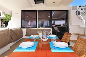 A dining area on a yacht with a table set for two, a bottle of wine, and a bowl of snacks. - Sun-Kissed Sailing Adventure in Zadar, Croatia (Biograd na moru)