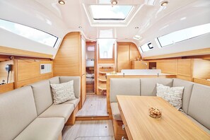 A compact interior with a dining area, seating, and a skylight. - Sun-Kissed Sailing Adventure in Islas Sarónicas (Alimos)