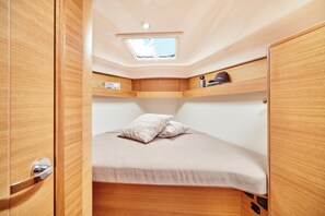 A compact, well-lit interior with a skylight, a bed with pillows, and wooden cabinetry. - Sun-Kissed Sailing Adventure in Islas Sarónicas (Alimos)